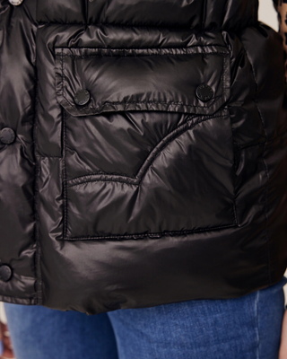 Close-up of the secure front pockets on the black puffer vest, highlighting the practical design for riders.