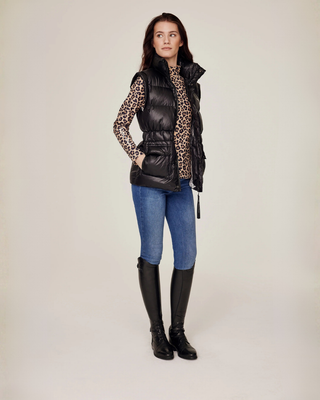 Side-angle full body shot of the unzipped black riding vest styled with a complete leopard print equestrian outfit.