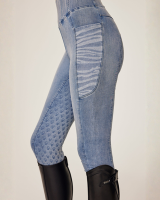 Side view of light blue jeans breeches featuring a zebra print phone pocket and signature skull-shaped silicone grip.