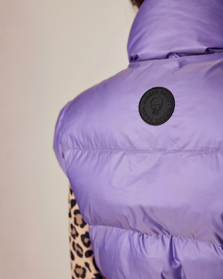 Detailed close-up of the Riders Denim logo on the back of the lilac puffer vest.