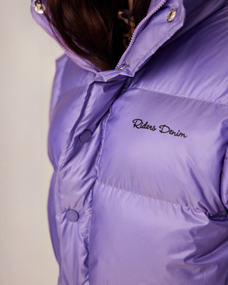 Close-up of the front of the lilac vest featuring the Riders Denim signature branding and zip detail.