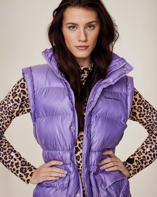 Front view of a model wearing the semi-glossy lilac riding puffer vest over a leopard print riding top with hands on hips.