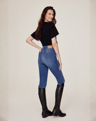 Full body side-back view of a model styled in Riders Denim original jeans breeches and a black equestrian t-shirt.