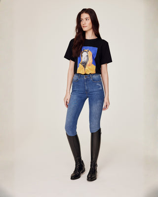 Full body front view of a model wearing Riders Denim original jeans breeches and a black horse print t-shirt.