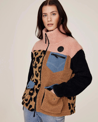 Side-angle view of the model with a hand in the pocket, highlighting the multi-pocket design and black sleeves.