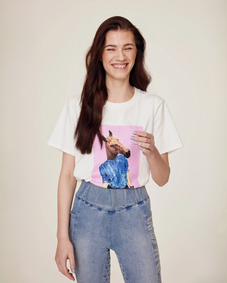Laughing model wearing the white horsie print t-shirt paired with light blue denim riding tights.