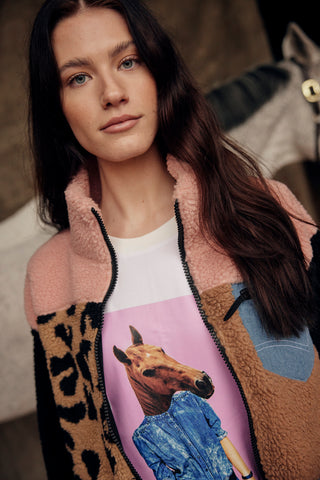 Lifestyle shot featuring the white horse print t-shirt layered under the pink and leo teddy jacket.